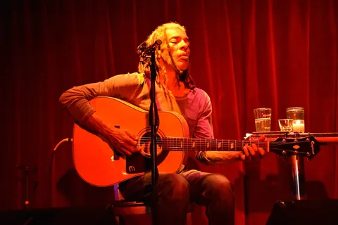 A guitarist singing on a small stage in front of a red curtain at Terra Blues