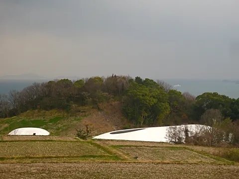 The low white shell of Teshima Art Museum on a green hillside