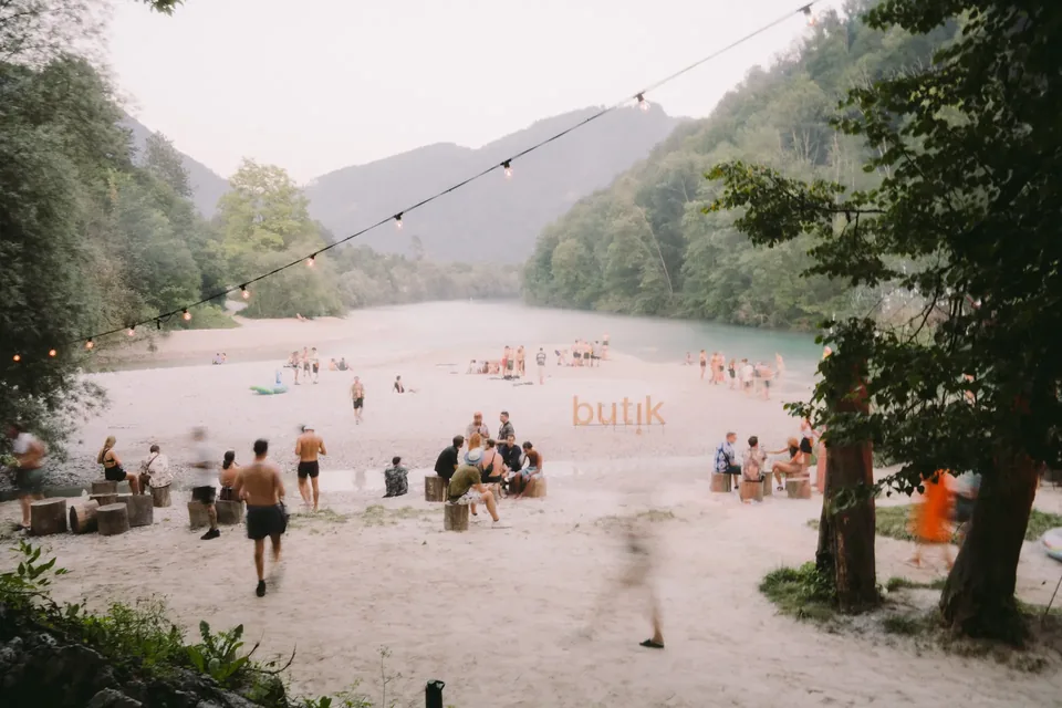 People on a pale shingle bank beside the turquoise Soča river