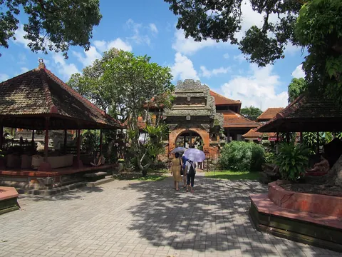 A paved courtyard with carved pavilions and gateways at Ubud Royal Palace