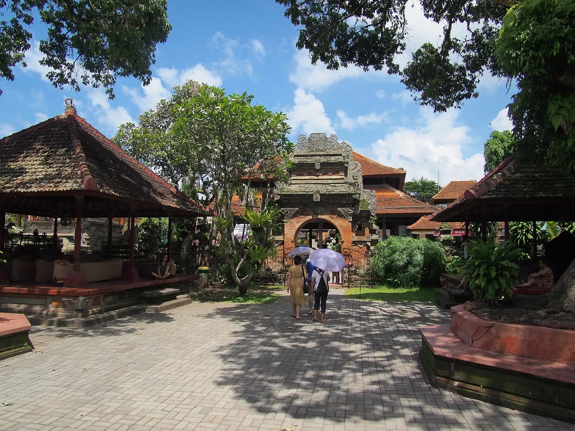 A paved courtyard with carved pavilions and gateways at Ubud Royal Palace