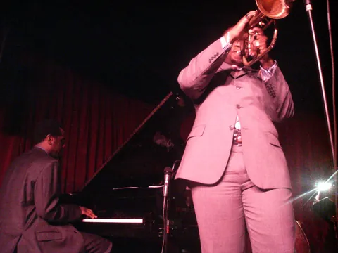 A trumpeter in a pink suit playing beside a pianist at the Village Vanguard