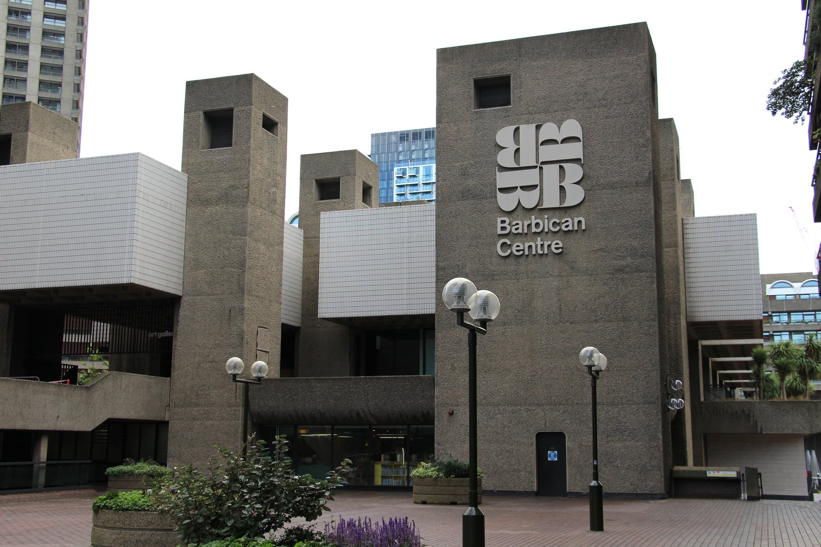 The Barbican Centre's Silk Street front: grey concrete towers, the stacked Barbican Centre logo on the wall and lamps on the forecourt