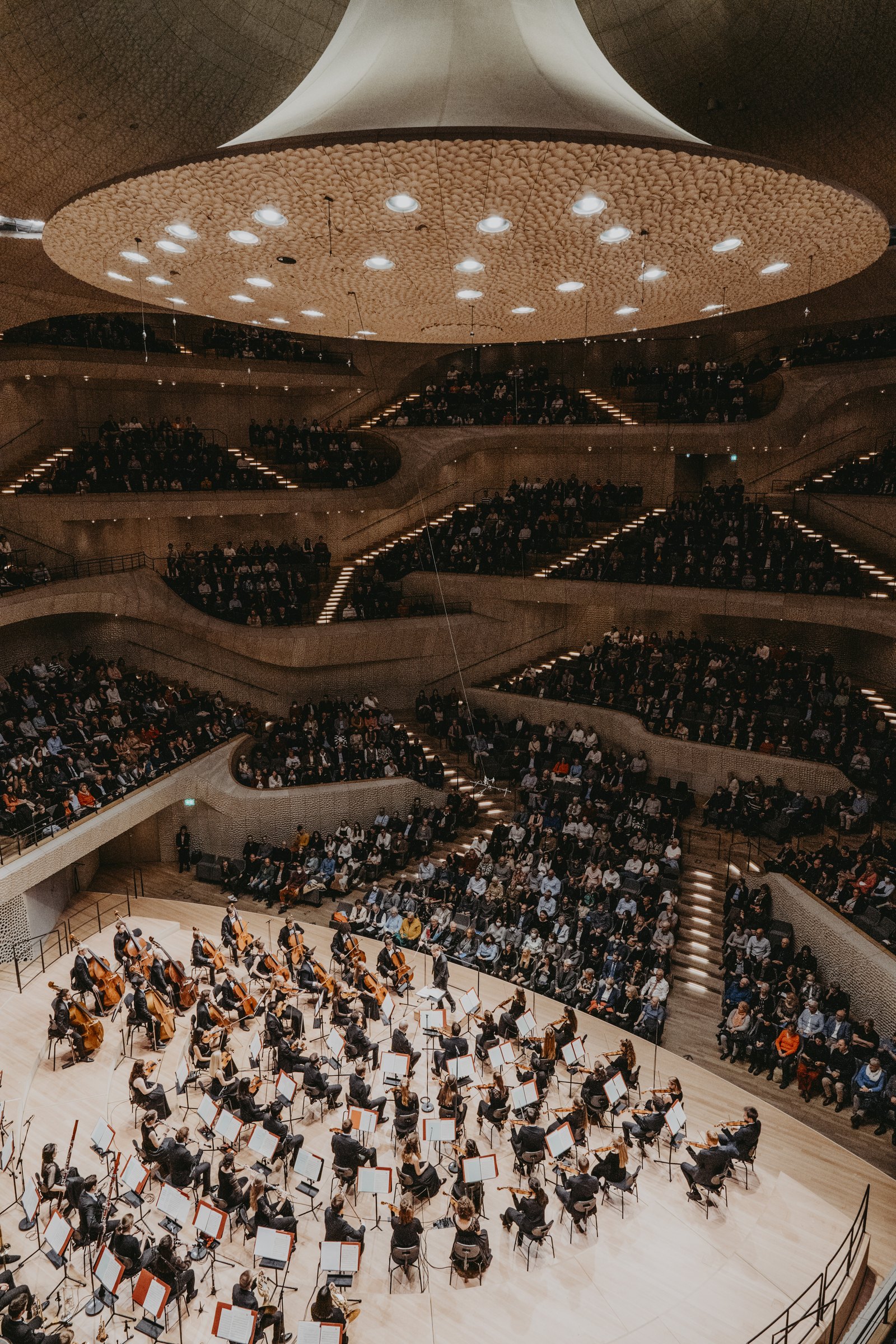 Looking down from high in the Grand Hall onto a full orchestra on the stage, the audience seated on terraces all around it