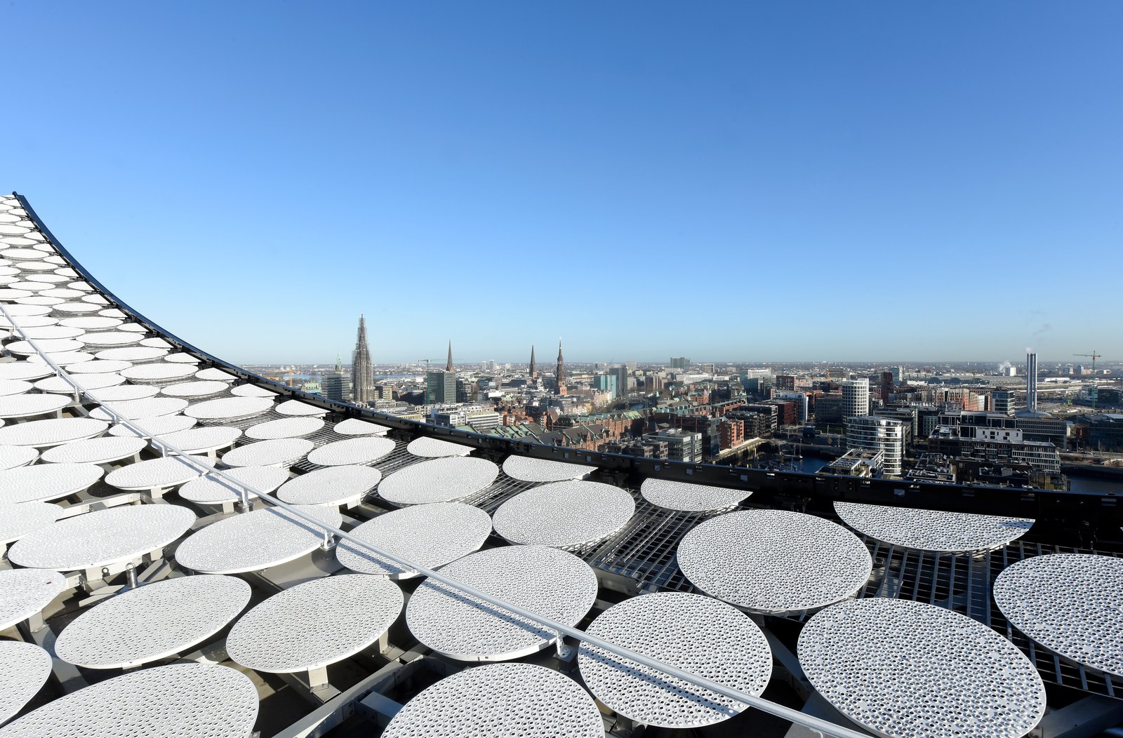 The view from the Plaza in clear winter light: the building's perforated white panels in front, the Hamburg skyline and church spires beyond