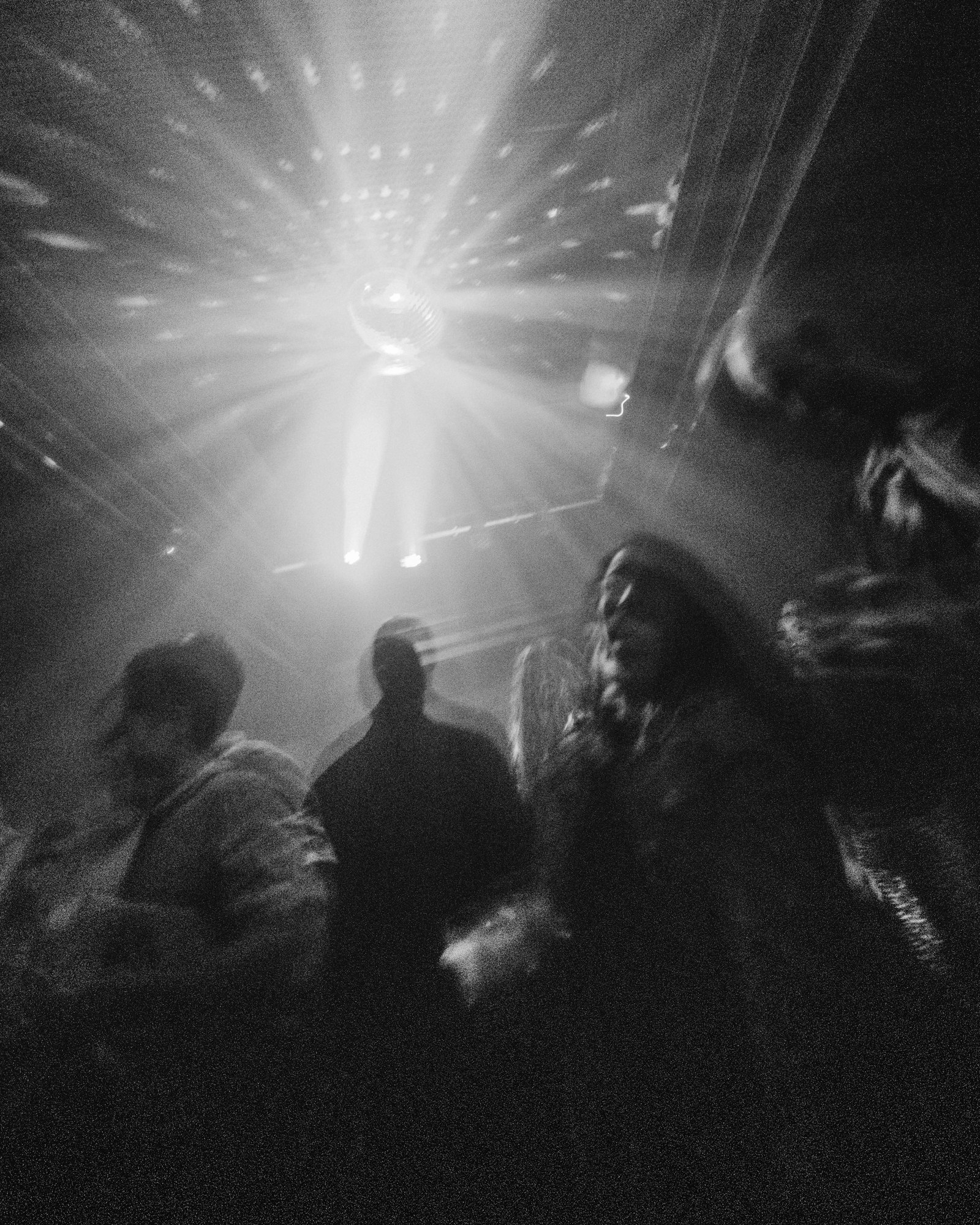 Black and white photograph of dancers under a mirror ball, light flaring out