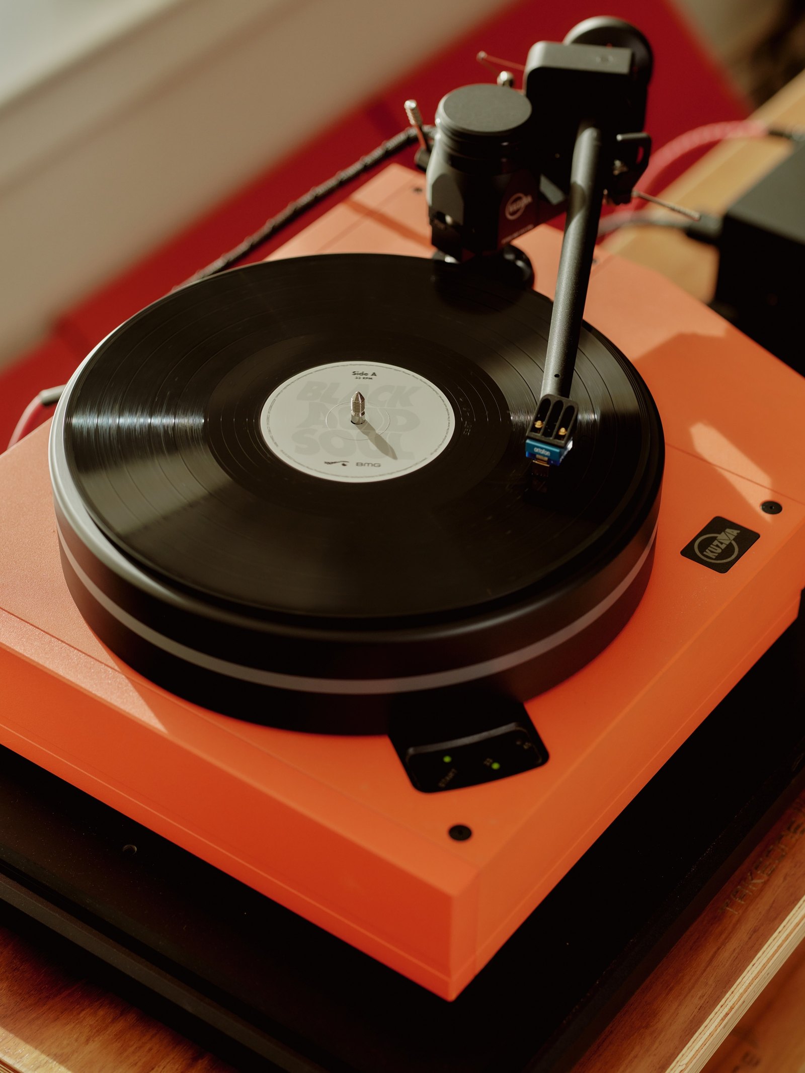 Close-up of an orange turntable with a record spinning and the tonearm down