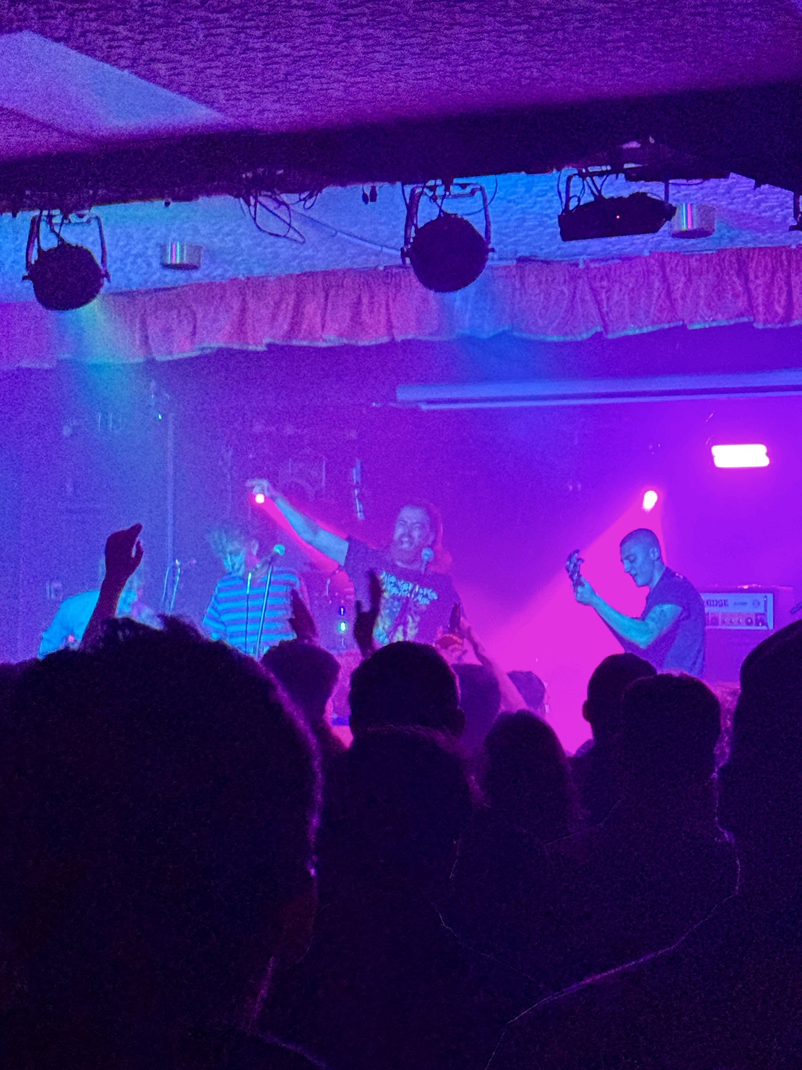 The band mid-set under purple stage light, raised arms in the crowd