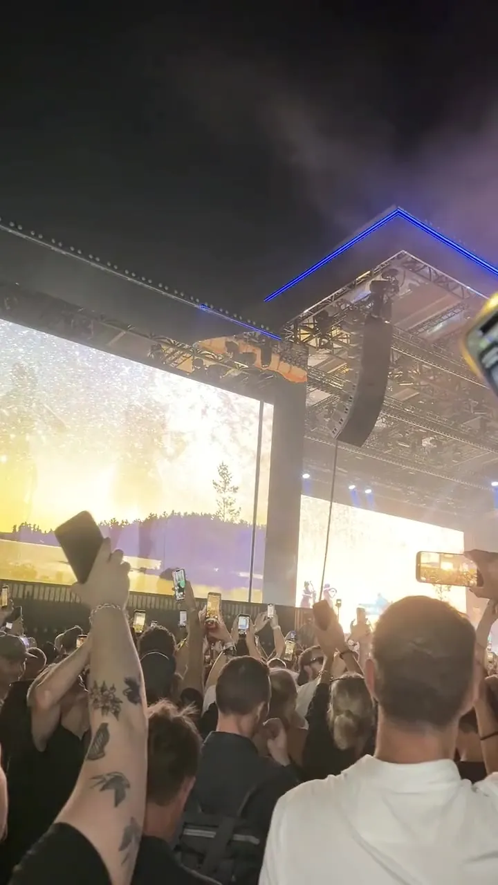 Hands up, stage smoke drifting across the square, the dome lit red, then the blue roof line